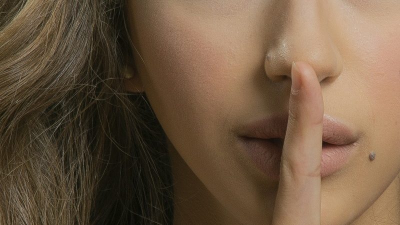 Woman with a finger on her lips shushing someone