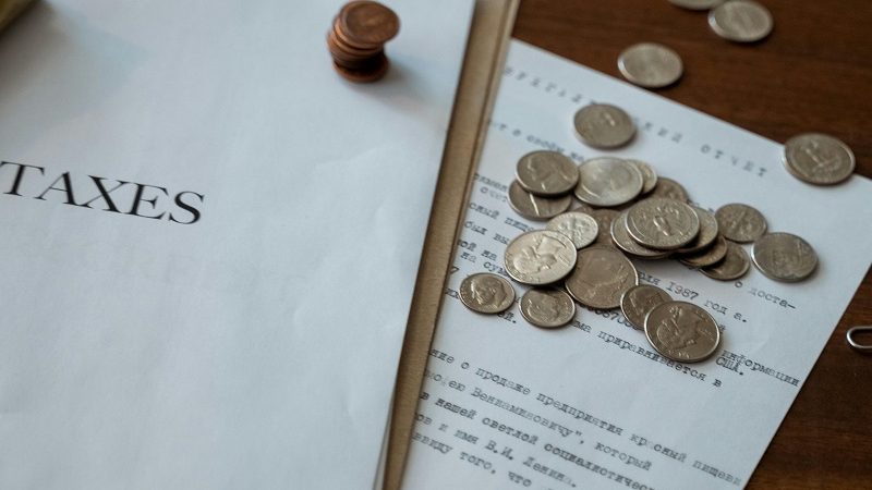 A paper with the word "Taxes" next to a pile of coins