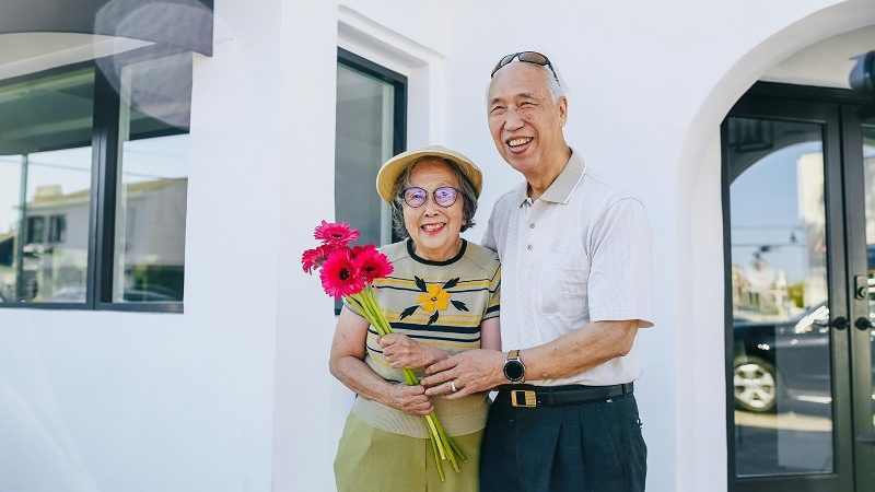 Elderly couple in front of their house, which is community property